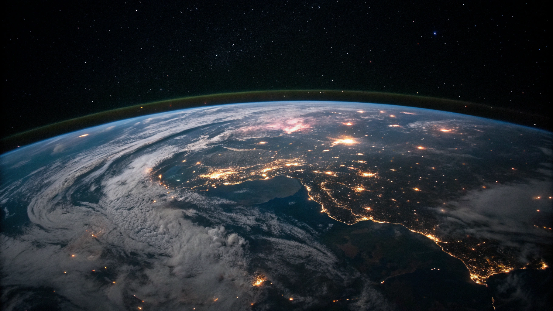 Earth photographed from space at night showing illuminated city lights along the dark planetary curve